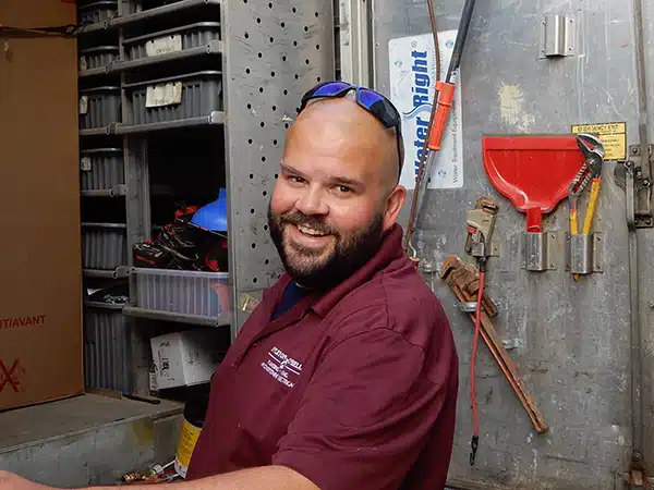 Appleton Campbell plumbing technician smiling and working out of the back of a plumbing truck.